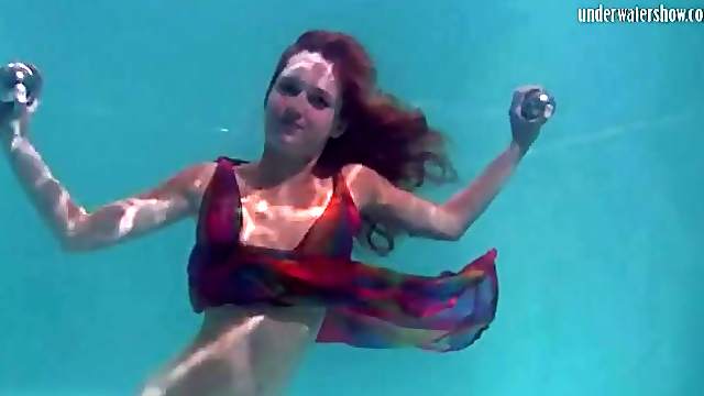 Young redhead swims in a pretty dress